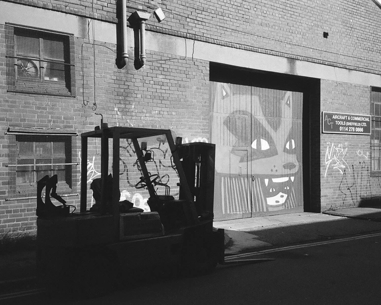 A forklift with some graffiti art behind it.
